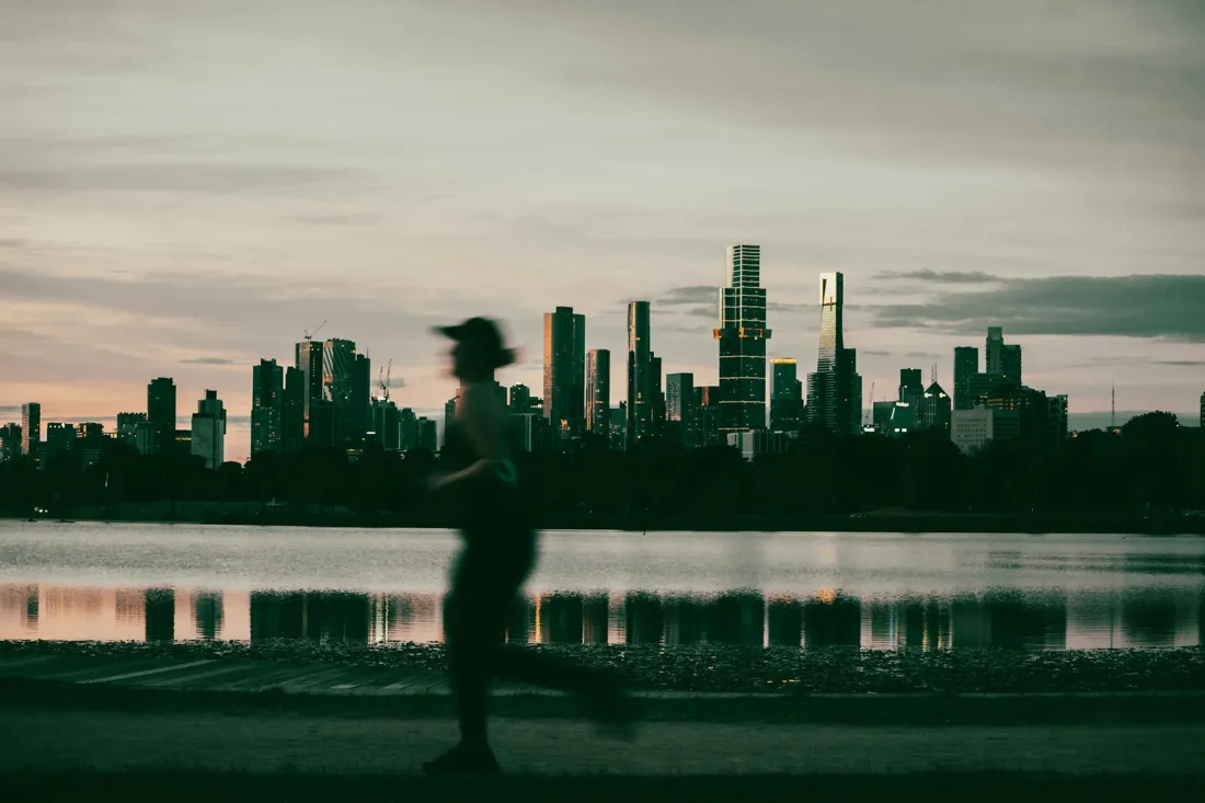 Homem correndo ao amanhecer diante da cidade
